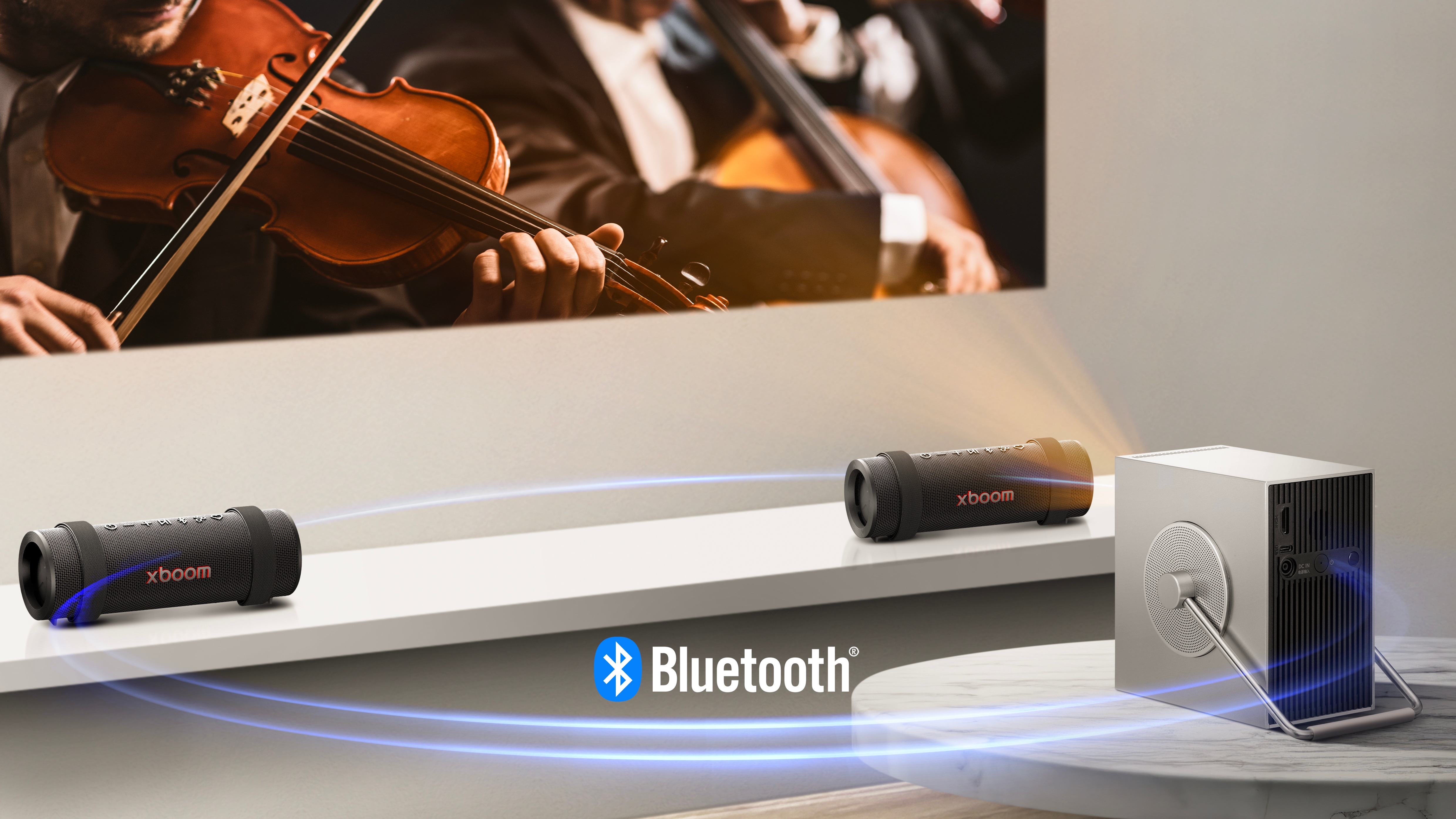 جهاز عرض LG CineBeam Q يعرض مشهد حفل موسيقي على الحائط، وتوجد وحدتان من XBOOM Grab على جانبي الشاشة أسفلها. خط ضوئي أزرق افتراضي يربط الأجهزة الثلاثة ليُظهر أنها متصلة عبر البلوتوث.